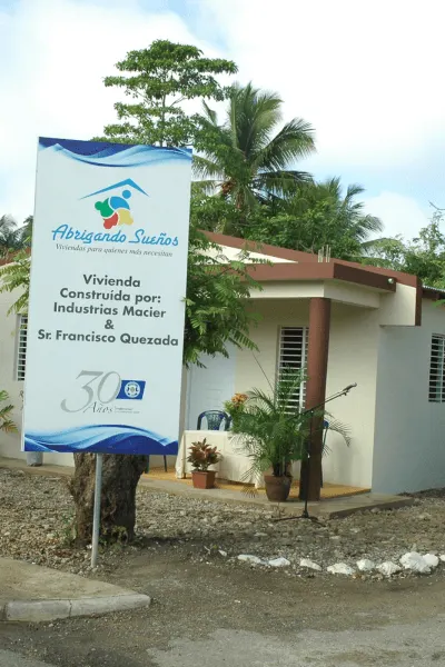 Vivienda nueva construida como parte del programa Abrigando Sueños, con cartel visible del proyecto y nombre de los patrocinadores.